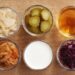 Sex skålar med fermenterad mat, bland annat kimchi, gurka och surkål