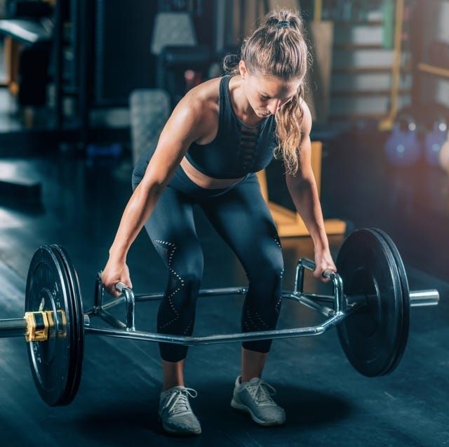 Kvinna lyfter en tung skivstång med trap bar på gymmet
